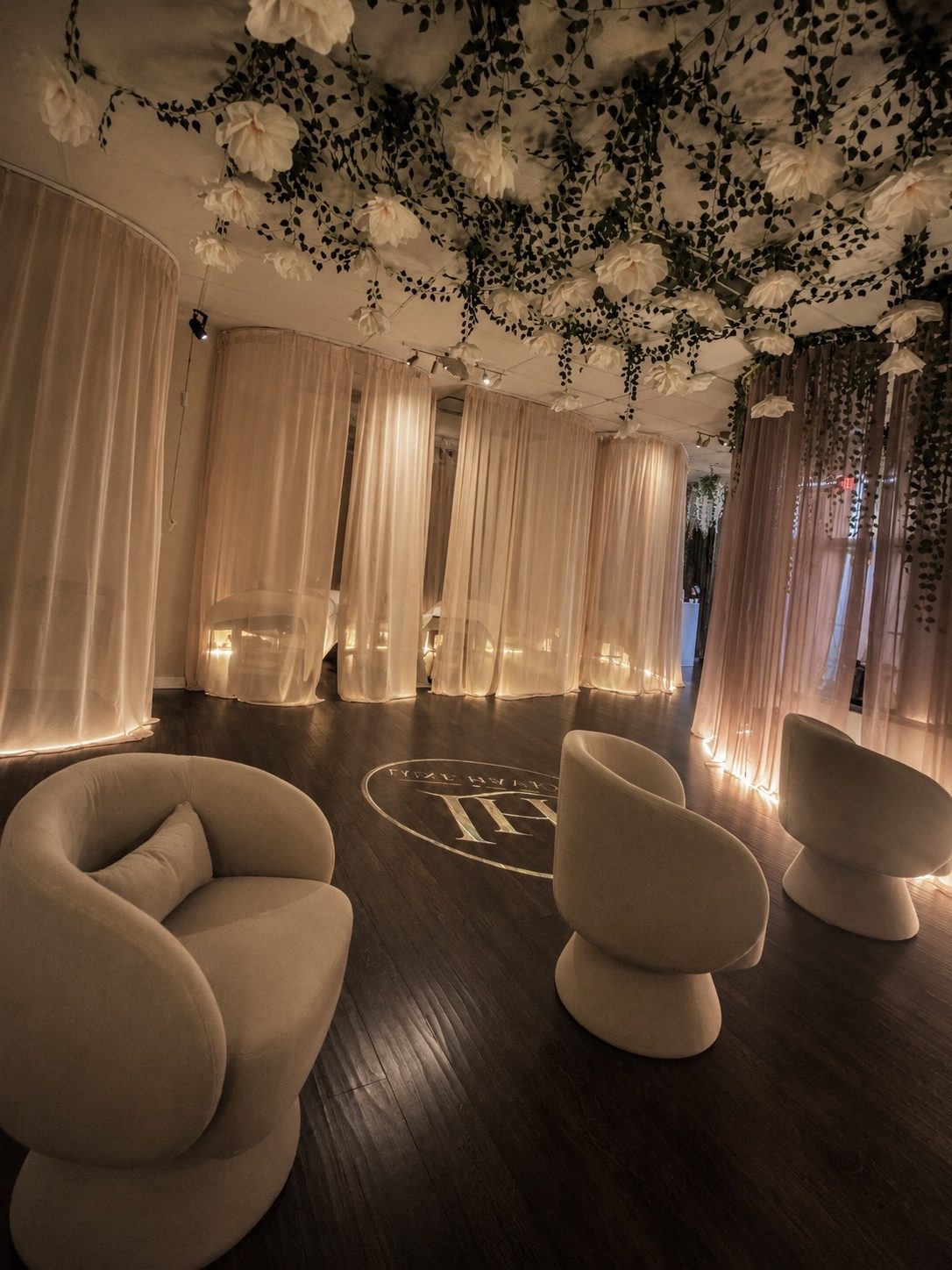 The open, curtained treatment area beneath the floral ceiling at Luxe Haven